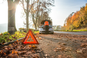 Pannenfahrzeug auf einer herbstlichen Strasse mit aufgestelltem Warndreieck